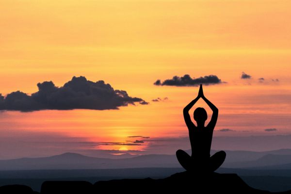 persona practicando yoga ayurveda en la cima de la montaña al atardecer